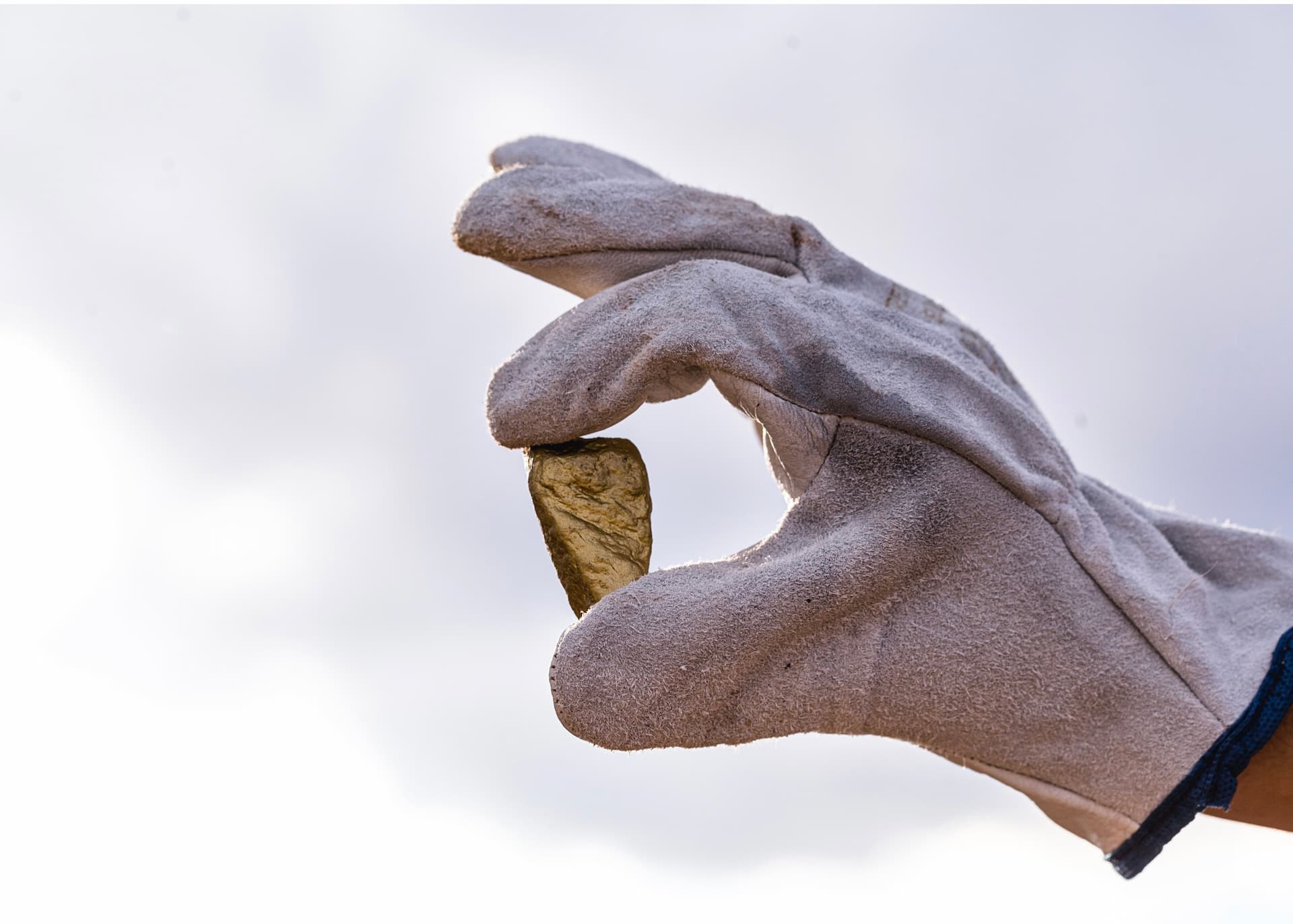 Gloved hand holding a large gold nugget